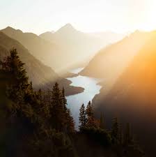 Green colored mountain scenery with trees and an overpowering yellow sunshine.